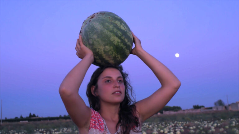 ragazza che tiene un'anguria in testa all'imbrunire