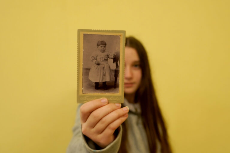 ragazza con in mano una foto in bianco e nero di una bambina